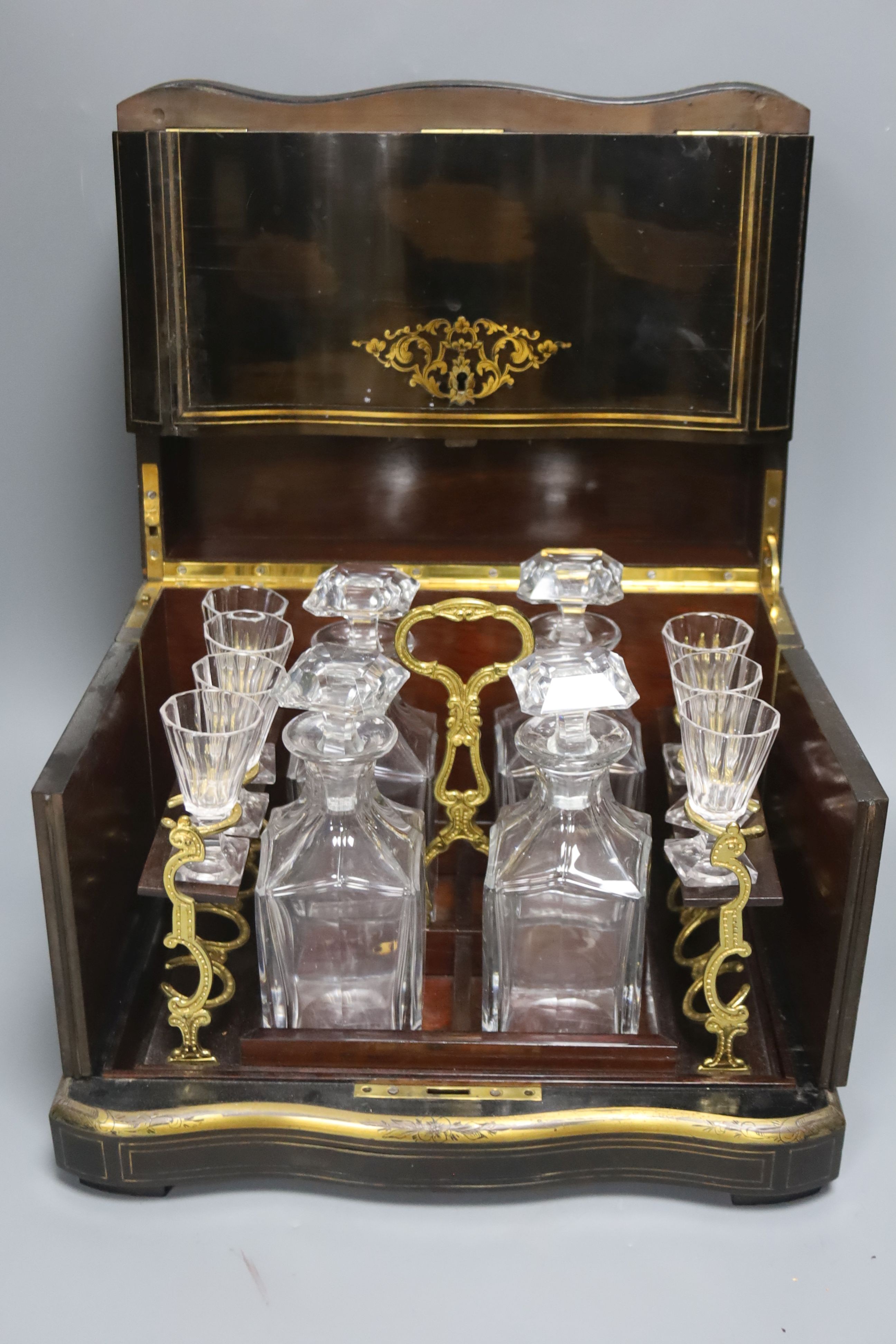 A mid-19th century French ebonised and brass-inlaid decanter case, fitted four decanters and seven glasses on removable tray (incomplete), W 35cm